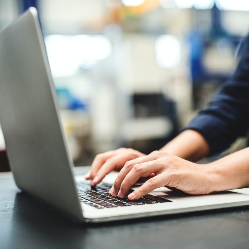 an-industrial-woman-engineer-in-a-factory-with-laptop-typing-